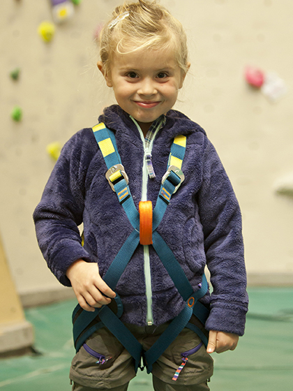 Niño escalador con arnés completo.